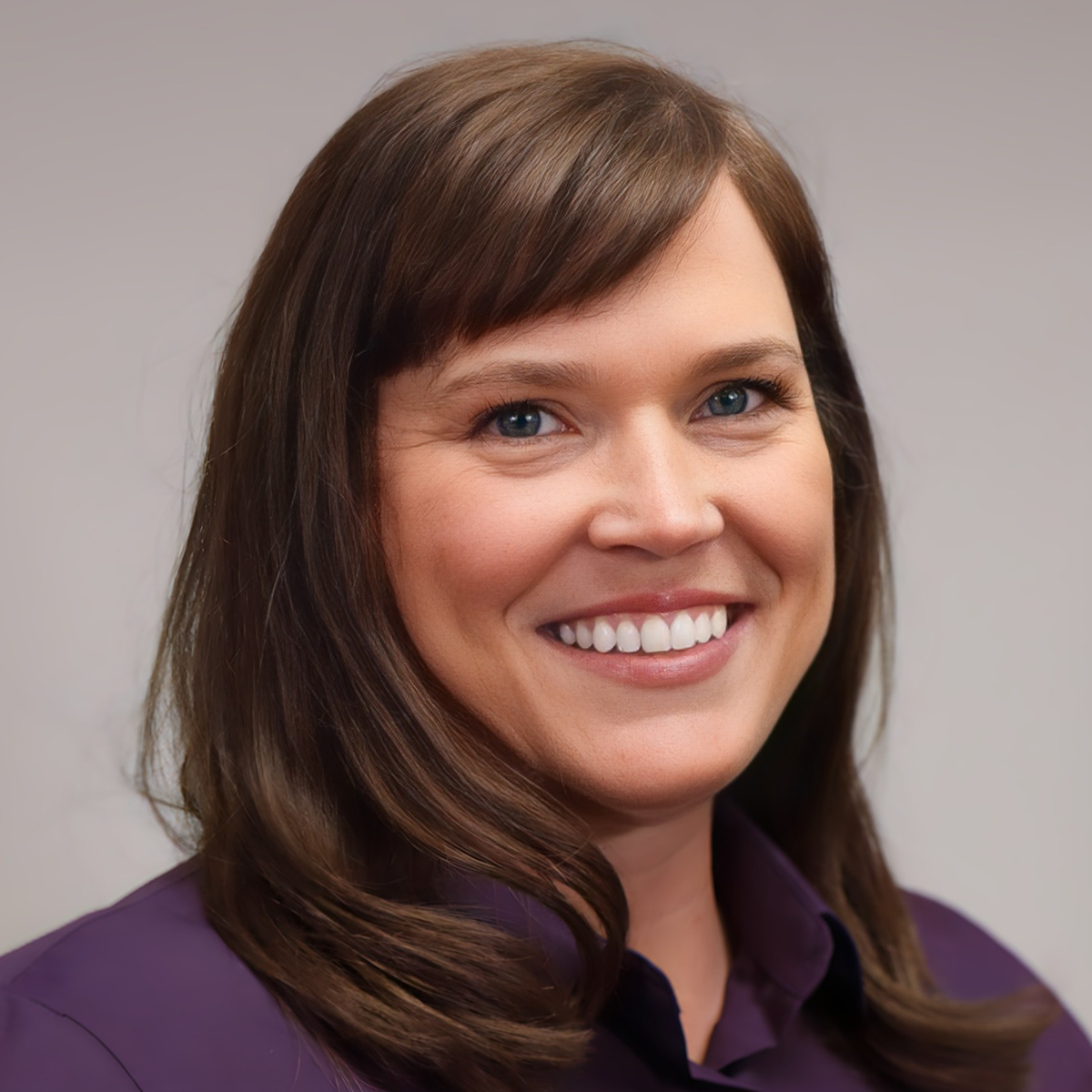 A woman with long brown hair wearing purple shirt.