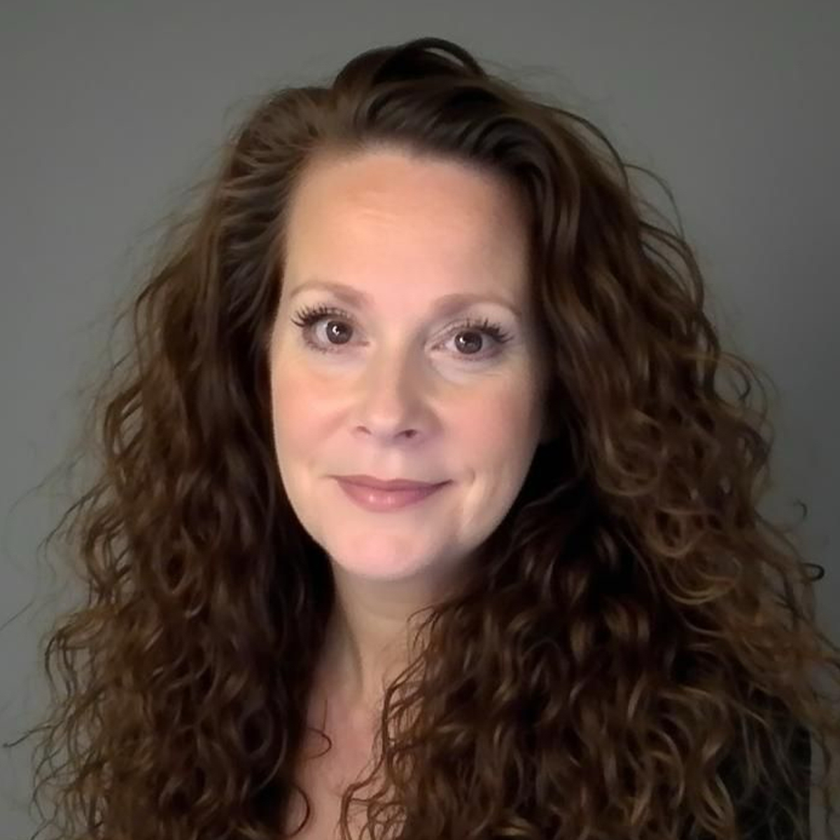 A woman with long brown hair and a smile.
