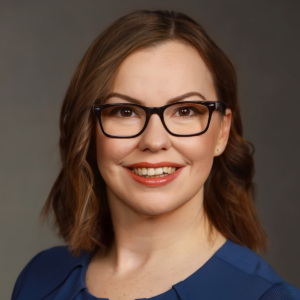 A woman with glasses is smiling for the camera.