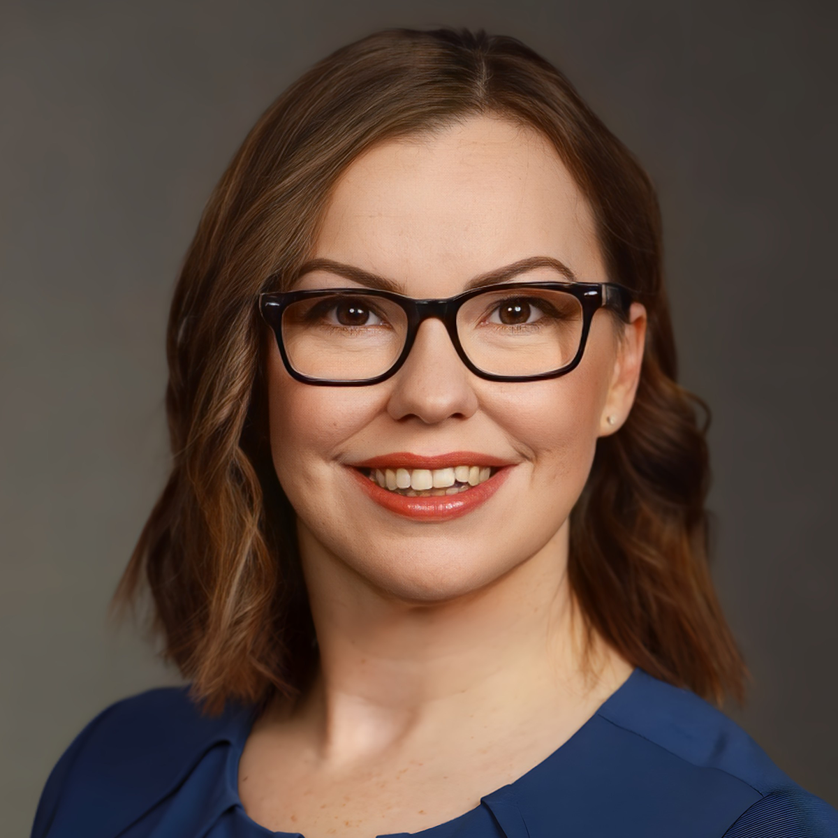 A woman with glasses is smiling for the camera.