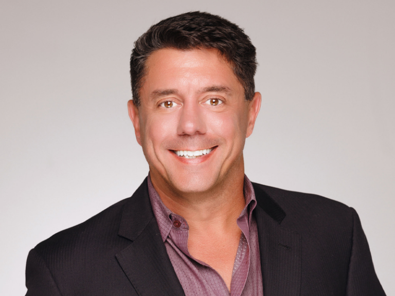 A man in a suit and purple shirt
