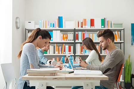 A group of people sitting at tables in front of books.