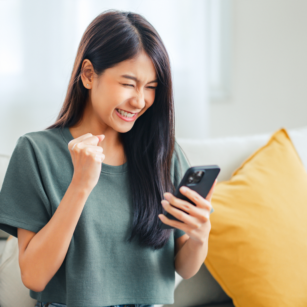 A woman is holding her phone and smiling.